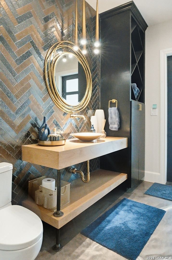 Powder bath with brass mirror and herringbone tile